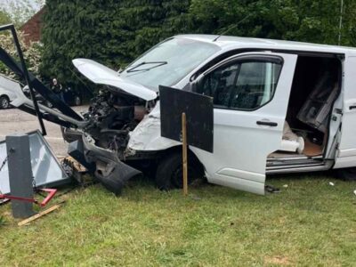 White van with destroyed frontage lodged into pub sign on grass